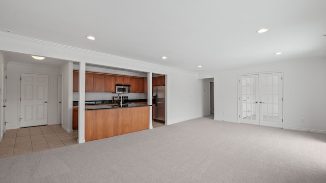 kitchen featuring open floor plan, appliances with stainless steel finishes, dark countertops, and light colored carpet