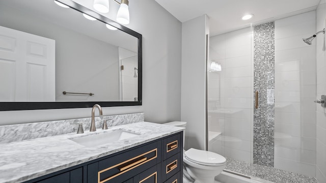 bathroom featuring toilet, vanity, and a shower stall