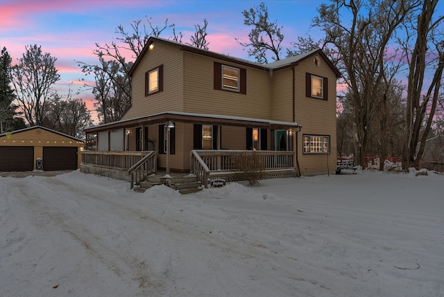 view of front of home featuring a detached garage, a porch, and an outdoor structure