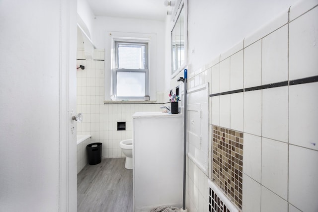 bathroom featuring wood finished floors, tile walls, toilet, and vanity