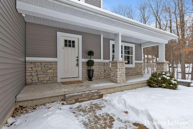 snow covered property entrance with covered porch