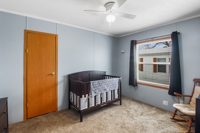 bedroom with ornamental molding, light colored carpet, ceiling fan, and a crib