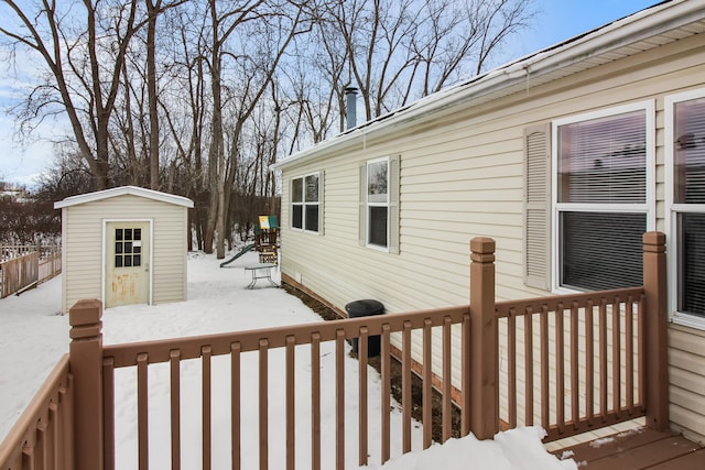 snow covered deck featuring a storage unit and an outdoor structure