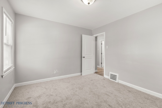 carpeted spare room featuring baseboards and visible vents