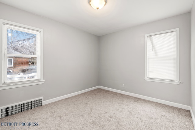 unfurnished room with carpet, visible vents, and baseboards