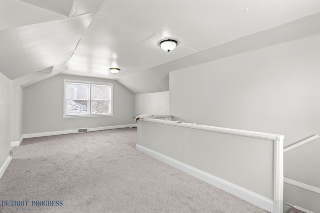 additional living space featuring light carpet, lofted ceiling, visible vents, and baseboards