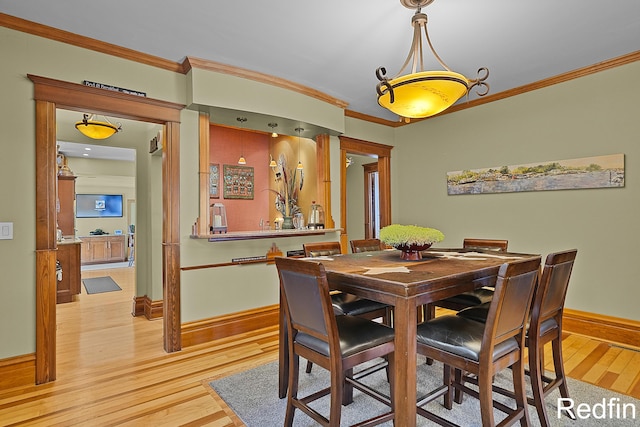 dining area with baseboards, light wood-style floors, and crown molding