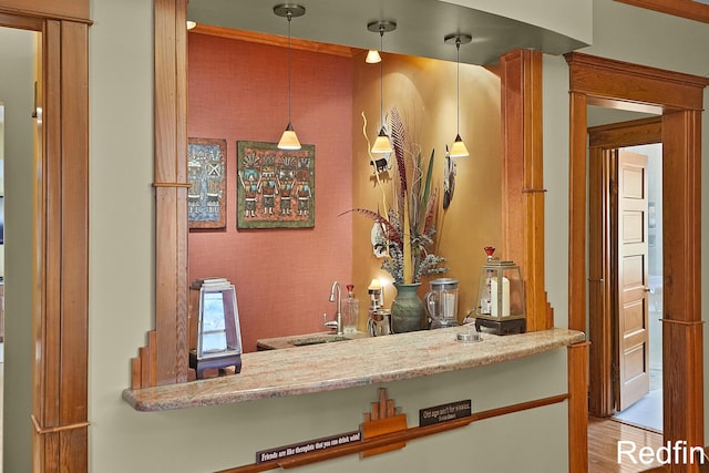 bar featuring a sink, hanging light fixtures, and wet bar