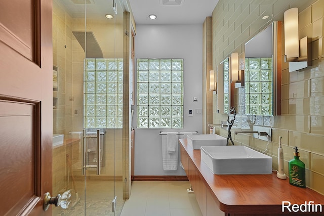 bathroom with double vanity, baseboards, a sink, tile patterned floors, and a shower stall