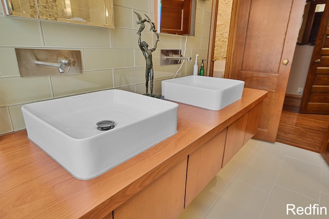 bathroom featuring double vanity, tile walls, a sink, and tile patterned floors