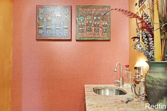 kitchen featuring a sink and light stone countertops