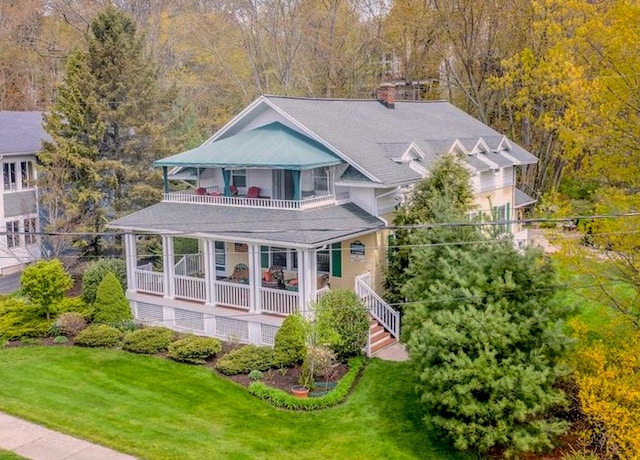 back of house with a balcony, a porch, a yard, and a chimney