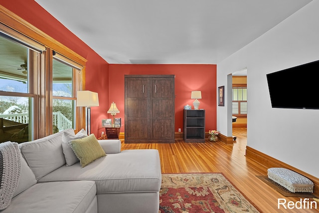 living area with a ceiling fan, light wood finished floors, and baseboards