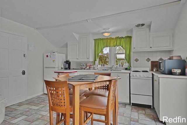 kitchen with light countertops, stone finish floor, white cabinets, and white appliances