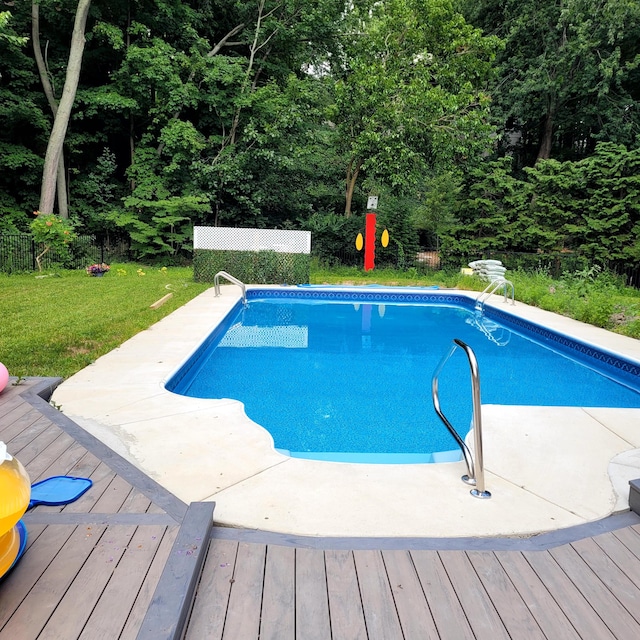 view of swimming pool featuring a lawn and a deck