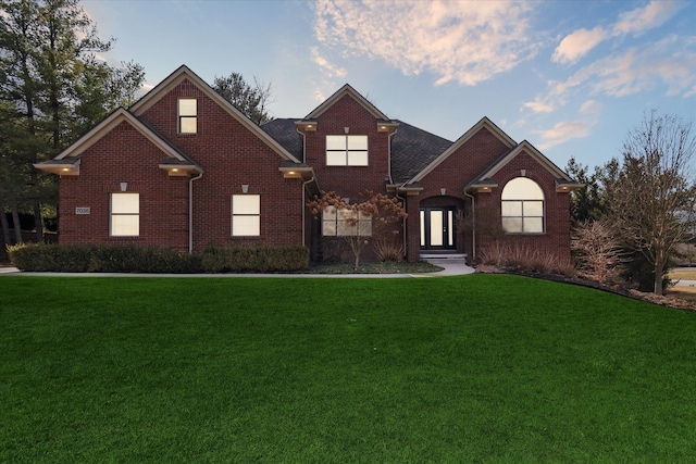 traditional-style home featuring brick siding and a front yard