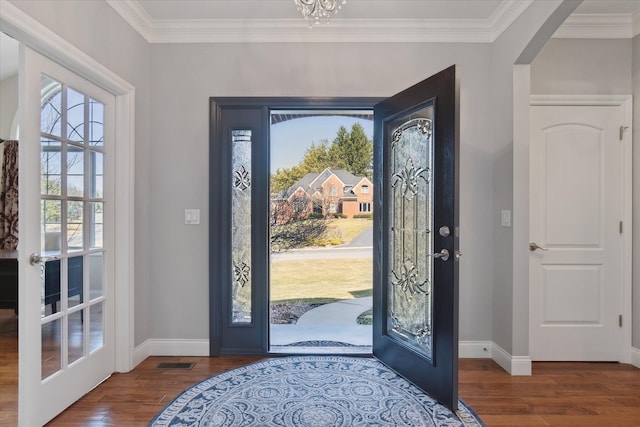 foyer entrance featuring visible vents, crown molding, baseboards, wood finished floors, and arched walkways