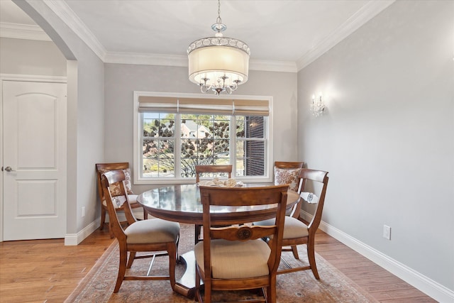 dining space with arched walkways, ornamental molding, baseboards, and wood finished floors