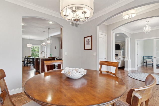 dining area featuring crown molding, a notable chandelier, a fireplace, and wood-type flooring