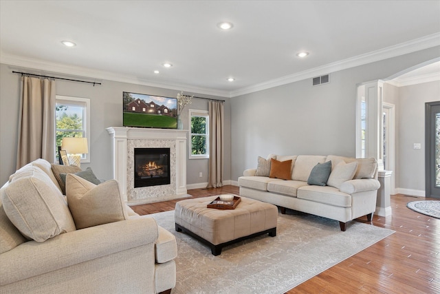 living room featuring visible vents, plenty of natural light, light wood-style flooring, and crown molding