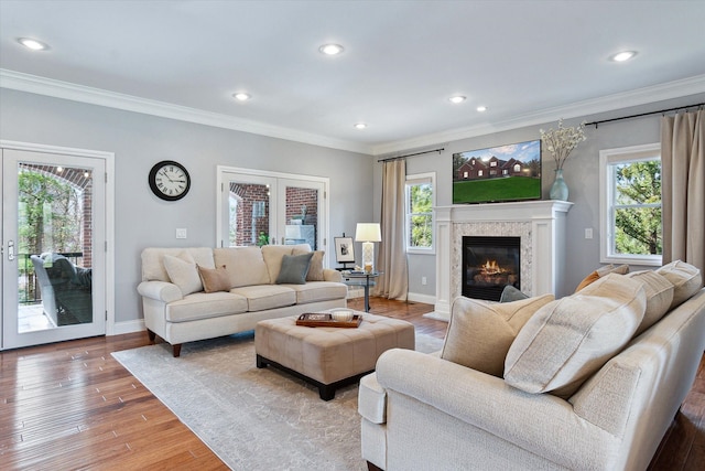 living area with plenty of natural light, light wood-type flooring, and ornamental molding