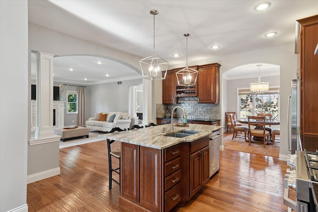 kitchen featuring a sink, arched walkways, light wood-style floors, and a breakfast bar