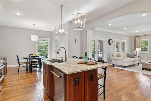 kitchen featuring a kitchen bar, light wood-style floors, arched walkways, and a sink