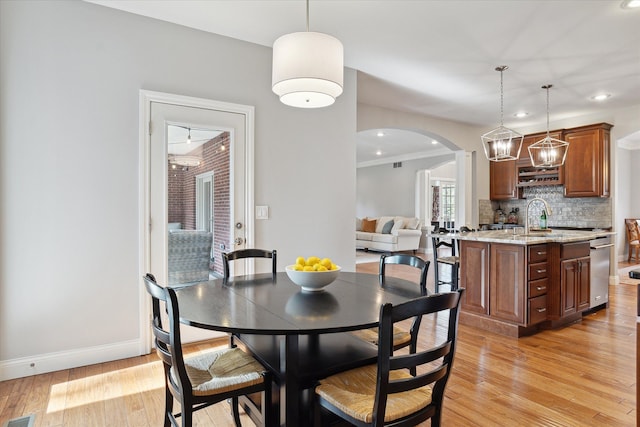 dining area with recessed lighting, light wood-style floors, arched walkways, and baseboards