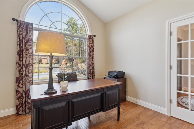 office space featuring baseboards, lofted ceiling, and light wood finished floors