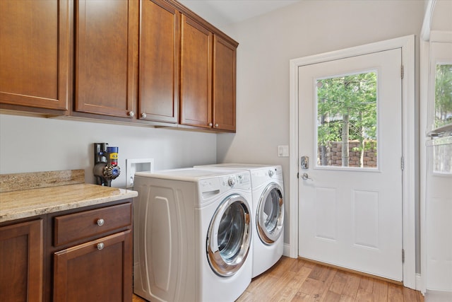 washroom with cabinet space, separate washer and dryer, and light wood-style flooring