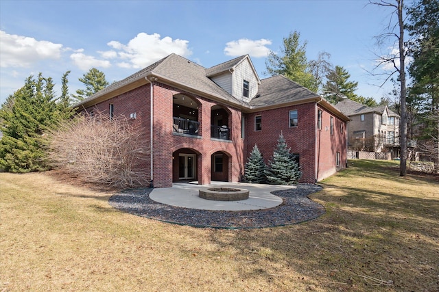 back of property featuring brick siding, a lawn, and a balcony