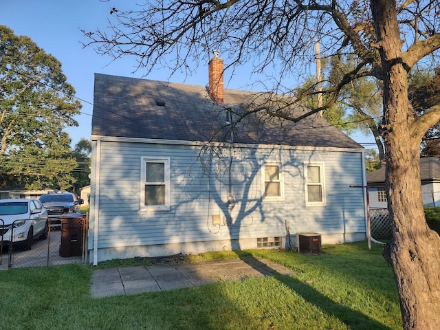 back of property with central AC, a yard, and a chimney