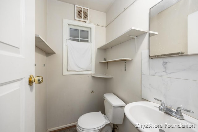 bathroom with toilet, visible vents, and a sink