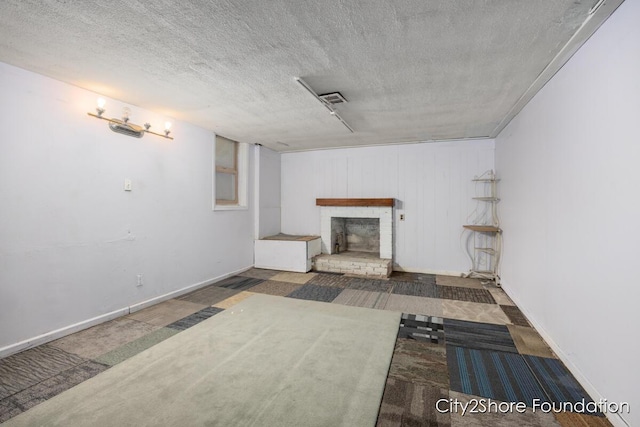 living area with a textured ceiling, a brick fireplace, and baseboards