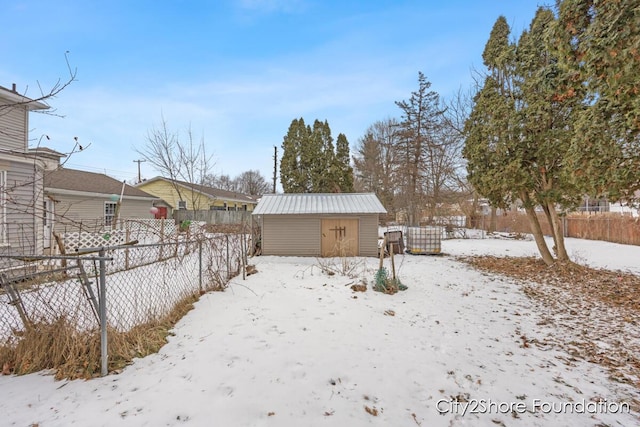 snowy yard with fence, an outbuilding, and a storage unit