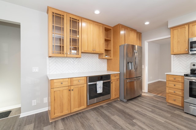 kitchen with wood finished floors, light countertops, stainless steel appliances, open shelves, and glass insert cabinets