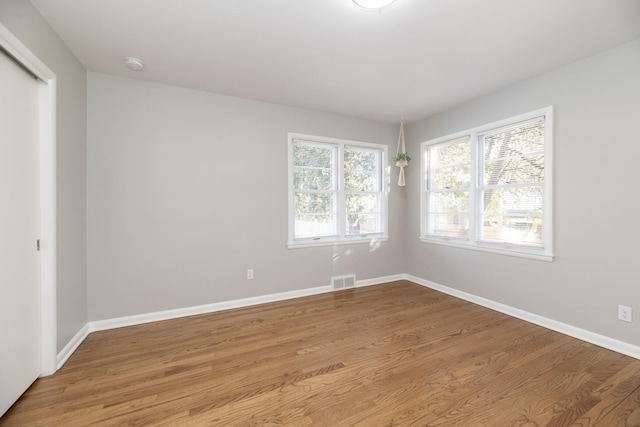 spare room with visible vents, wood finished floors, and baseboards