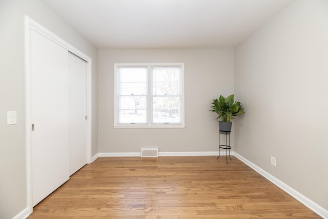 unfurnished bedroom with baseboards, visible vents, light wood-style floors, and a closet