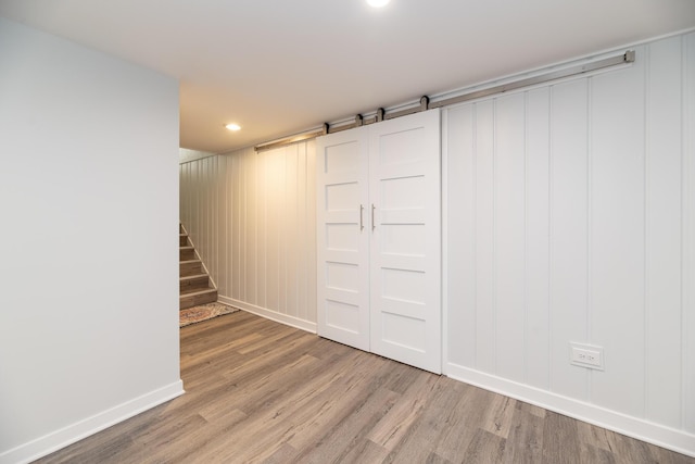 finished basement featuring baseboards, recessed lighting, stairway, and light wood-style flooring