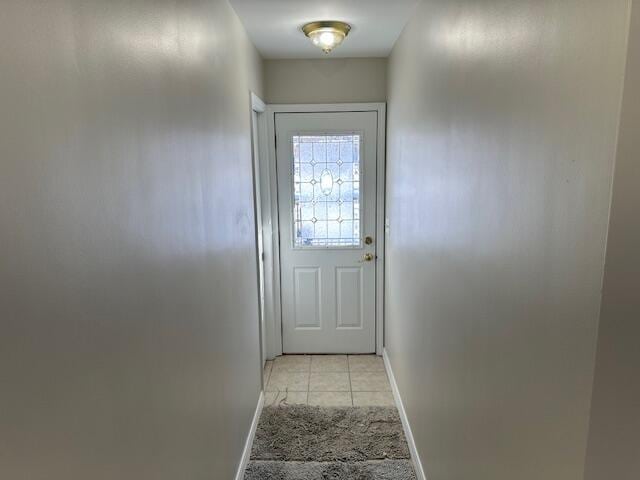 entryway featuring light carpet, baseboards, and light tile patterned flooring