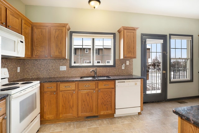 kitchen featuring white appliances, a sink, visible vents, decorative backsplash, and dark stone counters