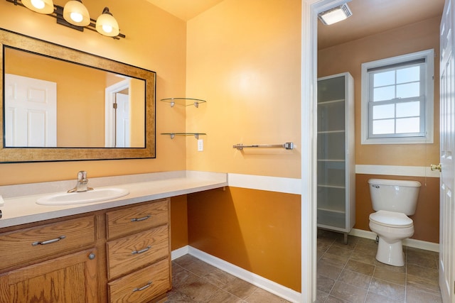 bathroom featuring a walk in closet, baseboards, vanity, and toilet