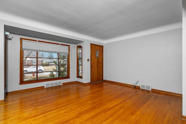 empty room with visible vents, baseboards, and wood finished floors