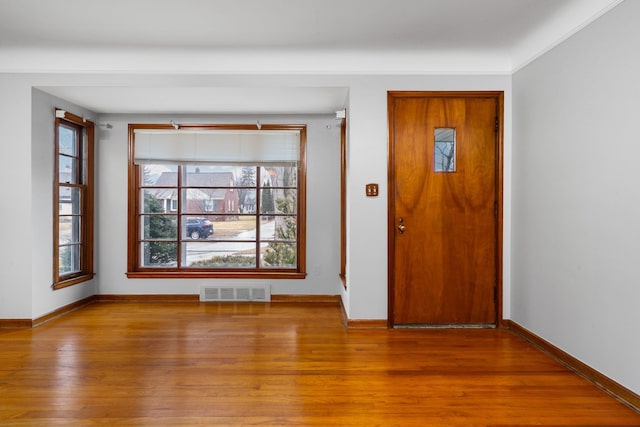 unfurnished room featuring wood finished floors, visible vents, and baseboards