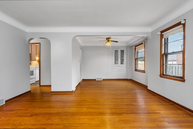 empty room featuring a ceiling fan, visible vents, baseboards, and wood finished floors