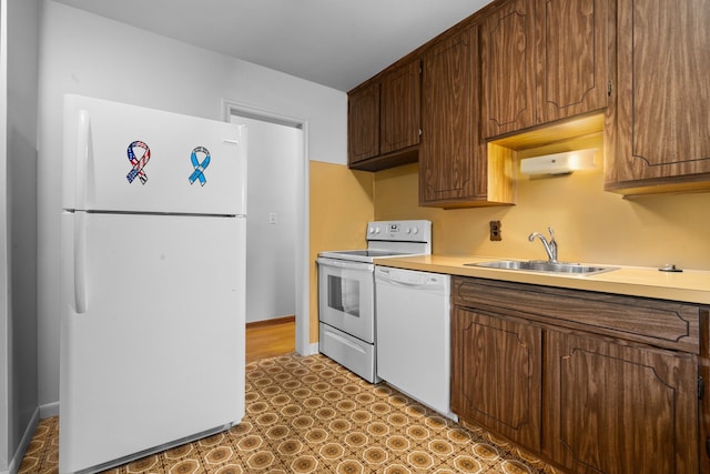 kitchen featuring light countertops, white appliances, a sink, and baseboards