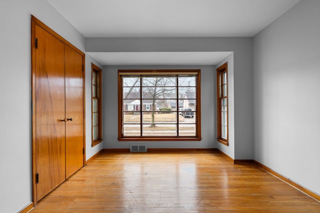 unfurnished bedroom with light wood-style floors, a closet, visible vents, and baseboards