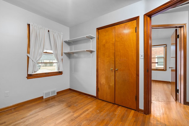 unfurnished bedroom featuring light wood finished floors, baseboards, multiple windows, and visible vents