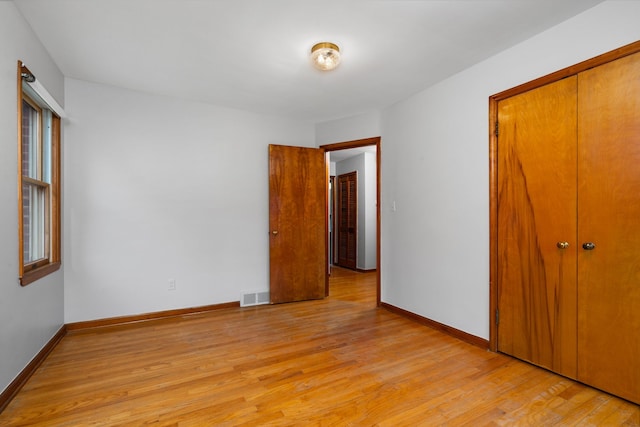 unfurnished bedroom with light wood finished floors, baseboards, visible vents, and a closet