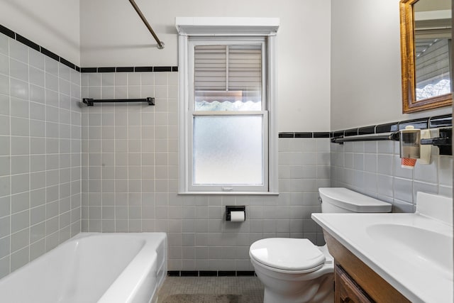 bathroom with tile patterned flooring, toilet, vanity, tile walls, and wainscoting